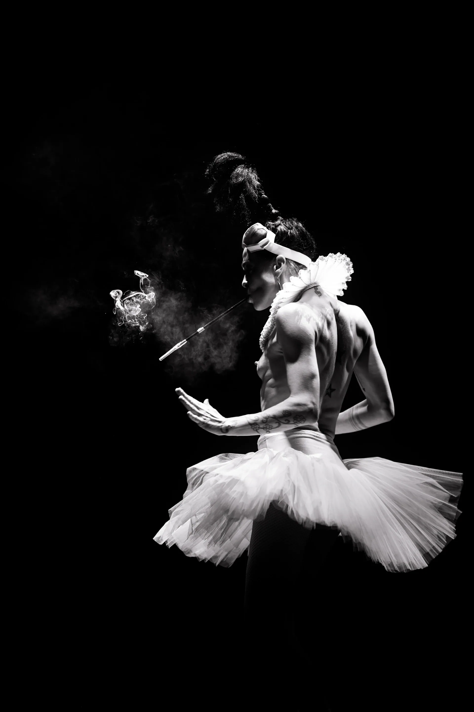 Two performers stand close together, one wearing a light-colored tutu.